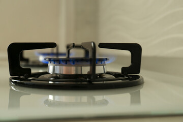 Gas burner of modern stove with burning blue flame, closeup