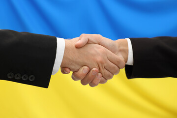 Diplomats shaking hands against flag of Ukraine, closeup