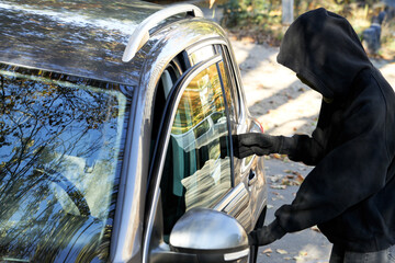 Thief breaking into modern auto. Car hijacking