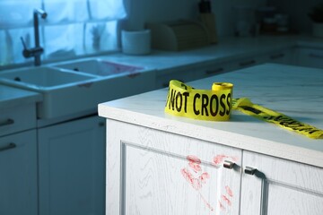 Yellow crime scene tape and bloody handprint on chest of drawers in kitchen. Forensic expertise