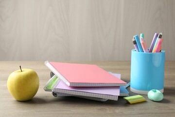 Doing homework. Notebooks, apple and stationery on wooden desk. Space for text