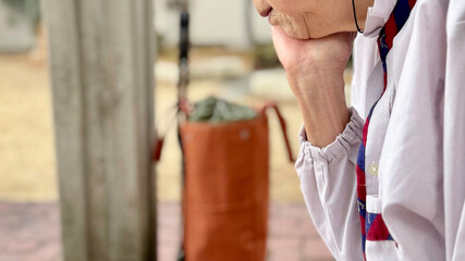 屋外で顎に手をやる高齢女性の部分アップ_ワイド