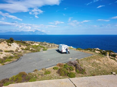 Couple outside their camper van near the sea with solar panels