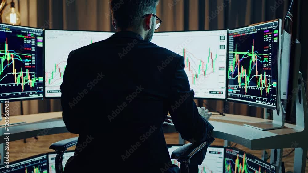 Poster expert trader analyzes market trends using multiple screens and technical charts in a modern office 