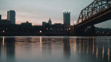 Urban skyline at dusk with a bridge reflected in the water.