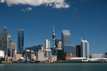 View onto skyline of Auckland as seen from a ferry towards Devonport on a summer day with perfect blue sky (Auckland, North Island, New Zealand)