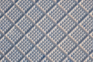 Close-up of a textured surface with diamond-shaped, raised patterns in a soft blue hue, creating a geometric and tactile abstract design.