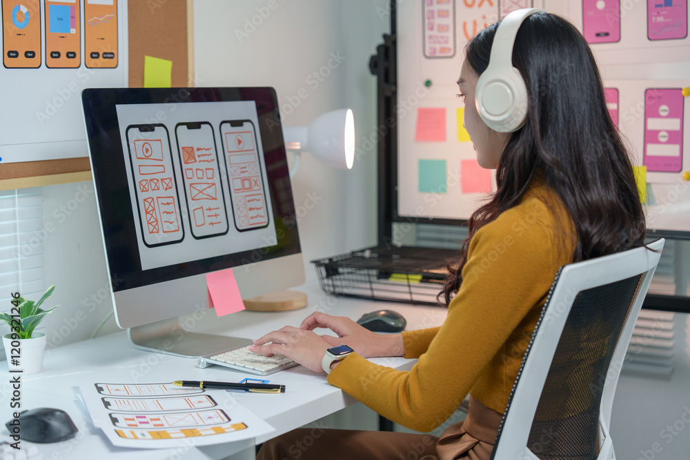 Poster creative web designer working with computer and headphones at her desk, developing a mobile applicat