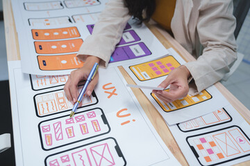 Web designer drawing sketches of mobile app templates, developing wireframe for user interface...