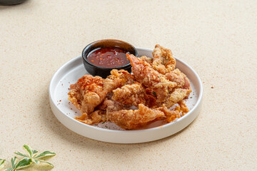 crispy chicken skin and chili sauce on white plate with light background