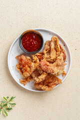 crispy chicken skin and chili sauce on white plate with light background