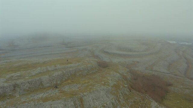 Aerial tracking shot over Mullaghmore Peak through mist with hikers enjoying the views. Ireland