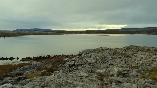 Drone glides low over limestone terrain, crossing Mullaghmore's seasonal lake. Burren national par