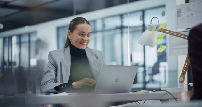 Young Hard Working Employee Achieves a Crucial Goal on Her Laptop Computer. Showing a Sense of Accomplishment. Manager Shares the Joy, Celebrating a Success Business Deal Behind Her Desk
