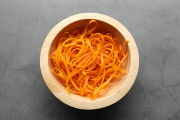 Fresh orange zest in bowl on grey textured table, top view