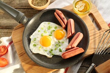 Tasty fried eggs with cut sausages served on wooden table, flat lay