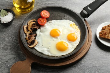 Tasty fried eggs with mushrooms served on grey table