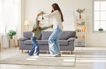 Full length photo of happy family of mother with daughter having fun and dancing in the living room...