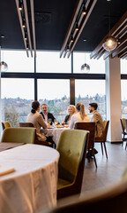 Smiling coworkers in restaurant talking during business lunch.