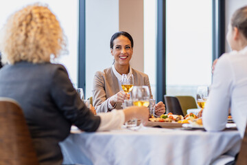 Portrait of businesswoman sitting with coworkers in restaurant during business lunch.