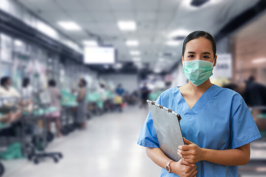 Female nurse wearing a mask and holding a clipboard in a bustling hospital ward, emphasizing medical care and professionalism.