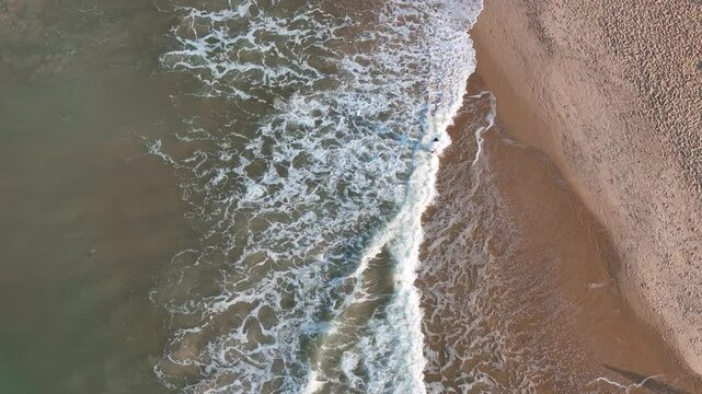 A top-angle drone shot of Goa&rsquo;s beach reveals the vibrant coastline, with turquoise waters meeting golden sands, dotted with umbrellas and lined by lush greenery.