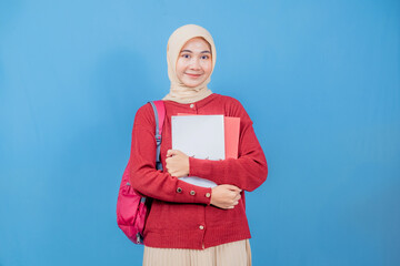 A woman wearing a red sweater and a white book is smiling. She is holding a red book and a pink bag