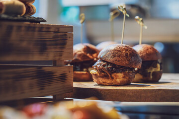 Delicious gourmet sliders served on a wooden platter with aromatic fillings, perfect for dining indulgence or event catering.