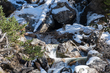 Mountain river flows in turbulent foaming stream in stone bed between huge boulders. Pure emerald water originates from mountain glaciers of North Caucasus. Dombay. Karachay-Cherkessia.