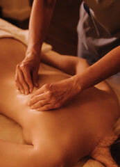 Hands of female chiropractor massaging shoulders of young woman lying on massage table. Concept of physical therapy treatment, neck pressure point. Soft focus, blurred, noise effect