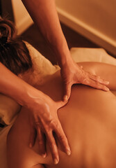 Fototapeta premium Hands of female chiropractor massaging shoulders of young woman lying on massage table. Concept of physical therapy treatment, neck pressure point. Soft focus, blurred, noise effect