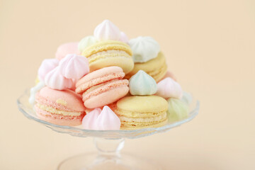 A crystal platter full of French macaroons and miniature meringues in pastel colors.