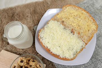 Bread with cheese, sweetened condensed milk, and butter. With white milk and snack on a table for breakfast	
