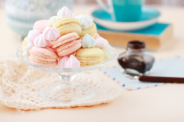 A crystal platter full of French macaroons and miniature meringues in pastel colors.