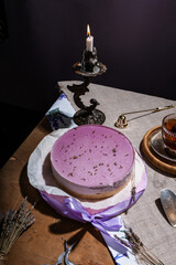 lavender cheesecake on shortcrust pastry with purple jelly in rustic style with tea in a glass cup, on a wooden background, lavender dessert, flatlay, still life with cake, candle, cozy tea party