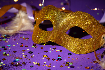 Beautiful carnival mask, ribbons and confetti on purple background, closeup