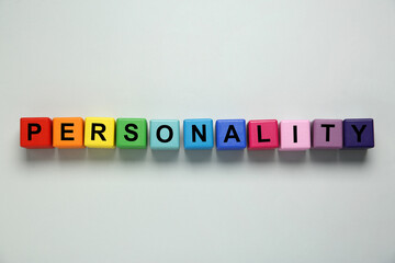 Word Personality made of colorful cubes with letters on light grey background, top view
