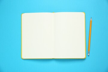 Blank notebook and pencil on light blue background, top view. Space for text