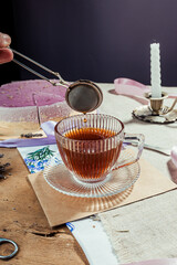 black tea in a glass retro cup on a wooden background with a metal teapot, rustic style, tea party, lavender cheesecake, purple dessert, flatlay, still life