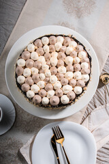 Kyiv cake with nuts, buttercream on a white cake plate, yellow runner, white dishes, espresso...