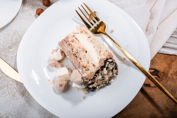 Kyiv cake with nuts, buttercream on a white cake pan in a cut on a white plate, espresso coffee, gold cutlery, Ukrainian desserts, nut cake, flatlay