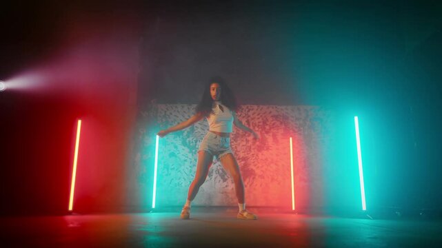 Self-confident black woman in sexy gown dancing alone in dance studio, portrait . Attractive mixed race female dancer performing hip-hop and dancehall style, full-length shot in modern school of arts
