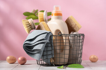 Basket with spring cleaning tools on pink background surrounded by decorative easter eggs. Easter...