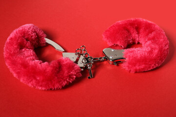 Bright fluffy handcuffs and keys on red background. Sex toy