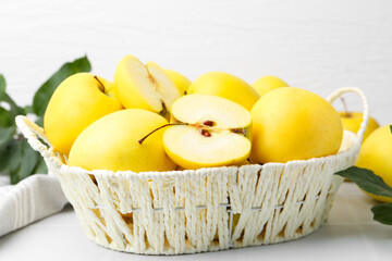 Fresh ripe yellow apples in basket on white tiled table, closeup