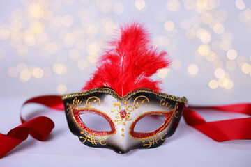 Beautiful carnival mask on color background, closeup. Bokeh effect