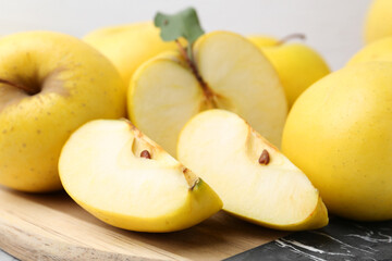 Whole and cut ripe yellow apples on table, closeup