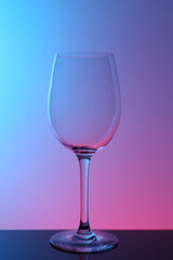 One empty glass on table against color background