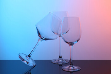 Empty glasses on table against color background