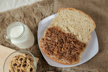 Bread with minced beef and union on a table. With white milk and snack for breakfast	
